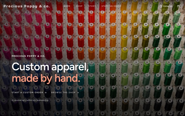 Precious Poppy homepage with colorful embroidery thread behind the headline ‘Custom apparel, made by hand.’